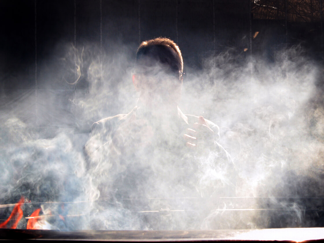 a salaryman behind incense smoke at Sensoji temple